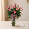 Pink roses arranged in a clear glass vase with a pink ribbon bow
