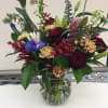 Mixed bouquet of roses, lilies, and irises in a glass vase