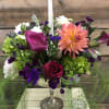 Colorful floral centerpiece with a white taper candle in a silver holder