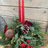 Holiday centerpiece with red candles, roses, pinecones, and evergreen branches