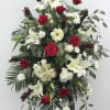 Standing floral spray with red roses, white lilies, and white daisies