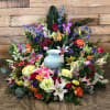 Colorful ring of mixed flowers surrounding a pale blue urn against a wood background