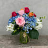 Bouquet of pink and red roses with blue hydrangeas in a glass jar