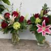 Two bouquets of red roses and pink lilies in glass vases