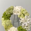 Circular floral wreath with white and green flowers on a black stand
