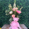 Pink teddy bear with a floral bouquet and sheer ribbon