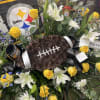 Football-shaped floral tribute with yellow roses and white lilies