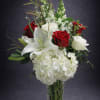 Red and white roses with lilies and hydrangeas in a glass vase
