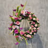 Large floral wreath with pink and lavender flowers on a black stand