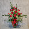Red roses arranged in a clear glass vase with baby's breath and greenery
