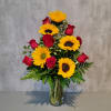 Bouquet of red roses and yellow sunflowers in a clear glass vase