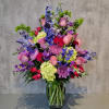 Large mixed bouquet of pink, purple, blue, and green flowers in a glass vase