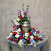 Red, white, and blue floral arrangement around a silver urn