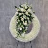 White floral funeral wreath with roses and lilies on a stand
