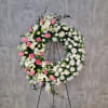 Large floral wreath with pink and white flowers on a black stand