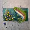 Large floral display with blue, yellow, and green flowers on an easel.