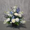 White and blue floral arrangement in a dark square vase