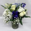 Pale white roses glow against a wash of cool blue hydrangea and