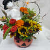 Halloween floral arrangement in a painted pumpkin container with a stuffed ghost