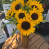 Sunflower bouquet in a tall gold vase on a wooden table
