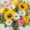Bouquet of yellow roses, sunflowers, white daisies, and pink carnations in a vase