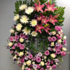 Large standing floral wreath with pink lilies, white spider mums, and roses