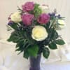 Pink and white roses arranged in a purple vase