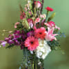 Tall mixed bouquet with pink lilies, gerbera daisies, orchids, and white hydrangea in a glass vase