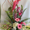 Tall pink floral arrangement in a rectangular vase with gerberas and orchids