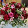 Bouquet of red and pink roses with greenery in a glass vase