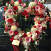 Heart-shaped floral wreath with red, pink, and white flowers on a vehicle