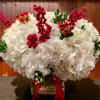 White hydrangea arrangement with red berry stems in a glass vase