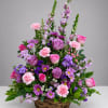 Pink and purple mixed flower arrangement in a wicker basket