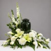 White lilies and mums arranged around a dark green urn