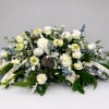 Large white floral arrangement with blue accents and ribbon
