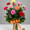 Colorful carnation bouquet in a glass vase with an orange ribbon
