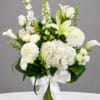 White flowers arranged in a clear glass vase with a white ribbon