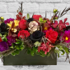 Rectangular floral arrangement with red, black, and purple blooms in a dark container
