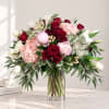 Mixed bouquet of red, pink, and white flowers in a clear glass vase