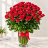 Red roses arranged in a clear glass vase with a red ribbon