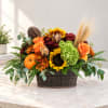 Autumn floral arrangement with sunflowers, roses, mums, and pumpkins in a wooden basket