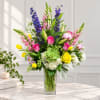Colorful bouquet in a clear glass vase with roses, lilies, and tall purple blooms
