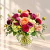 Mixed bouquet of roses, hydrangeas, and magenta blooms in a glass vase