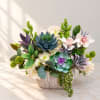 Mixed floral arrangement in a textured white vase with succulent accents