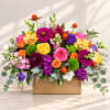 Bright mixed flower arrangement in a wooden box with roses and orchids