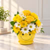 Yellow roses and white daisies in a smiley-face yellow pot