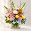 Mixed bouquet in a clear square vase with pink, yellow, and white blooms