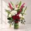 Tall bouquet of red and white flowers in a glass vase