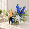 Mixed bouquet in a clear glass vase with blue, peach, and white flowers