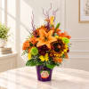 Orange and yellow mixed flower arrangement in a purple pot with a face decoration
